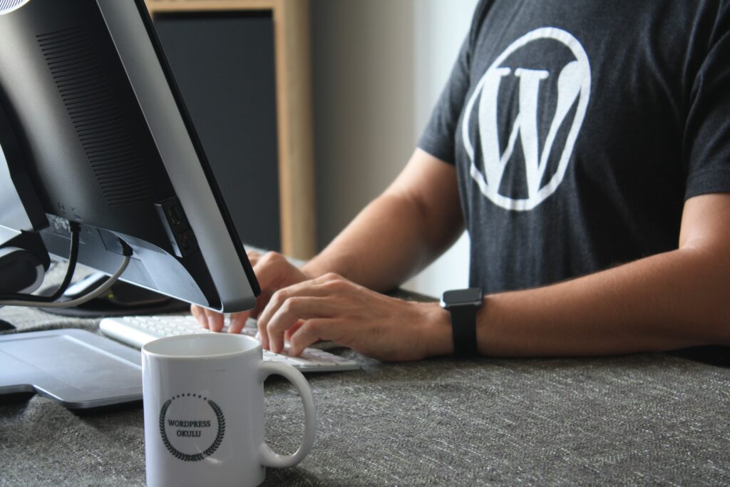 Man with WordPress logo on t-shirt typing on a computer.